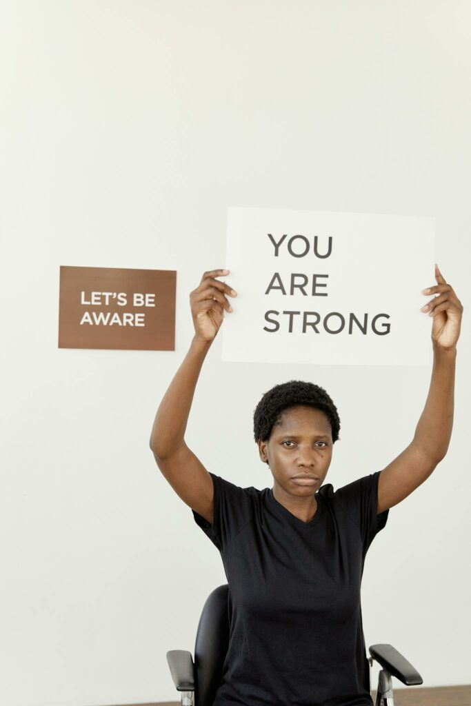 Femme résiliente tenant une pancarte “You are strong” – symbole d’espérance et de force intérieure, thème : espérance femmes résilientes.