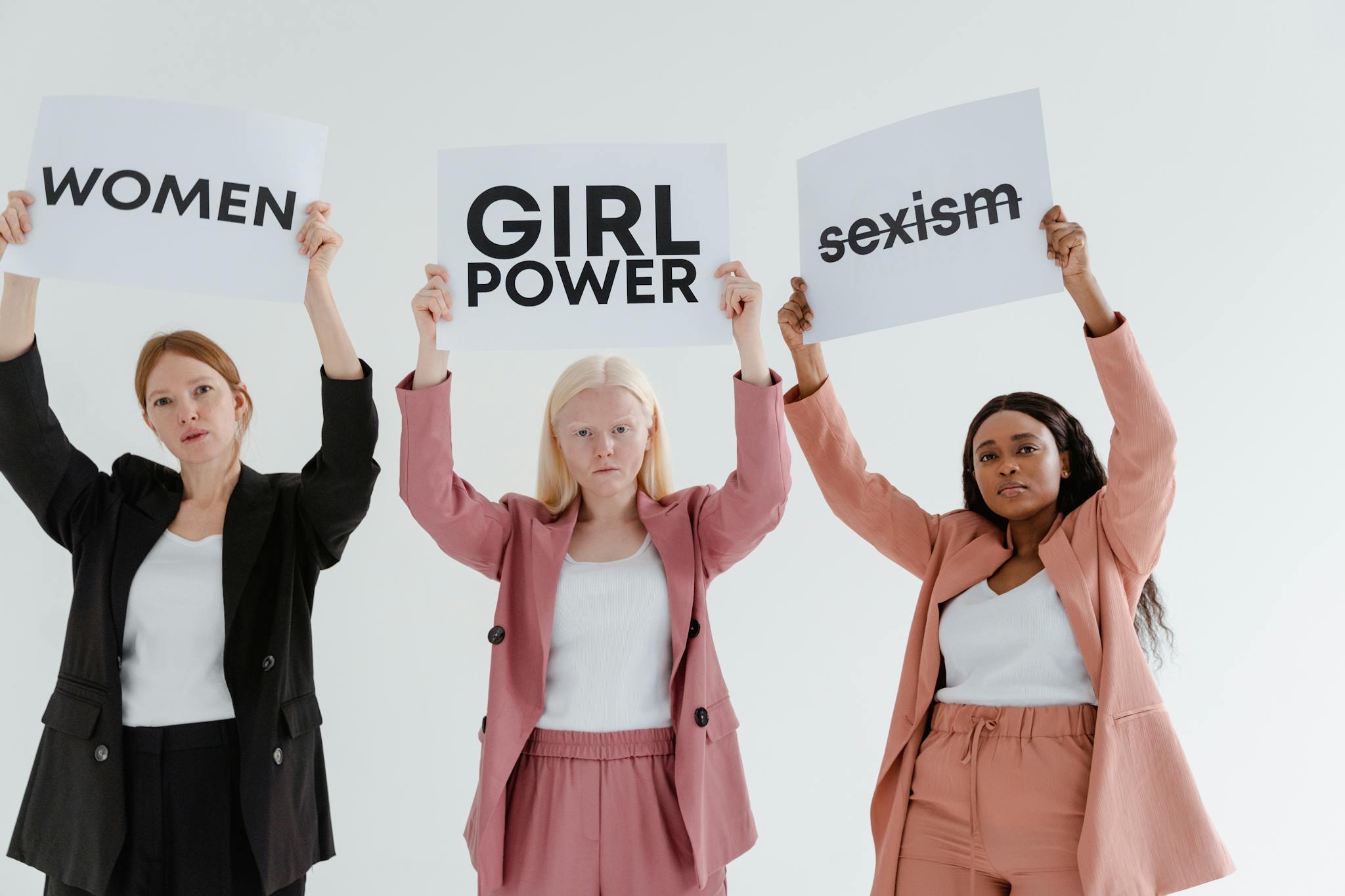 Trois femmes engagées brandissent des pancartes militantes, illustrant la mission plateforme engagée de Juste Une Voix pour l’égalité et la justice.