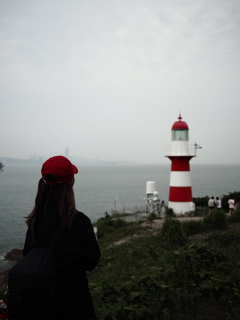 Femme face à un phare, symbole de solitude et de recherche de lumière